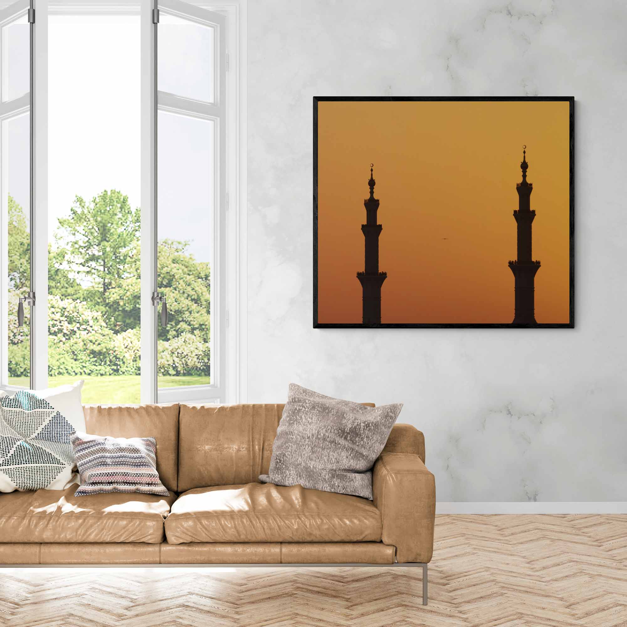 Silhouettes of two minarets against an orange sunset sky in Abu Dhabi.  Framed on a room