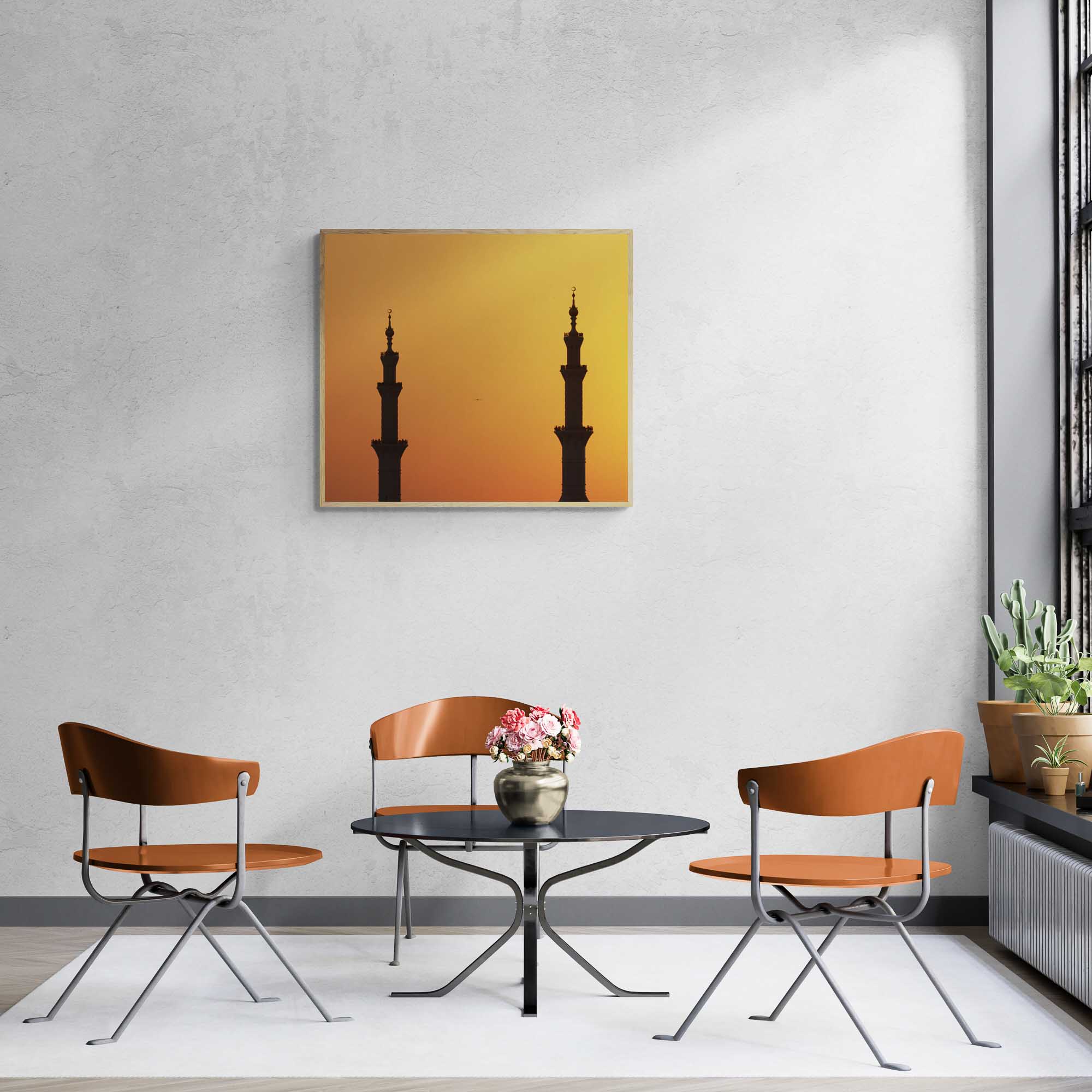 Silhouettes of two minarets against an orange sunset sky in Abu Dhabi.  Framed on a room