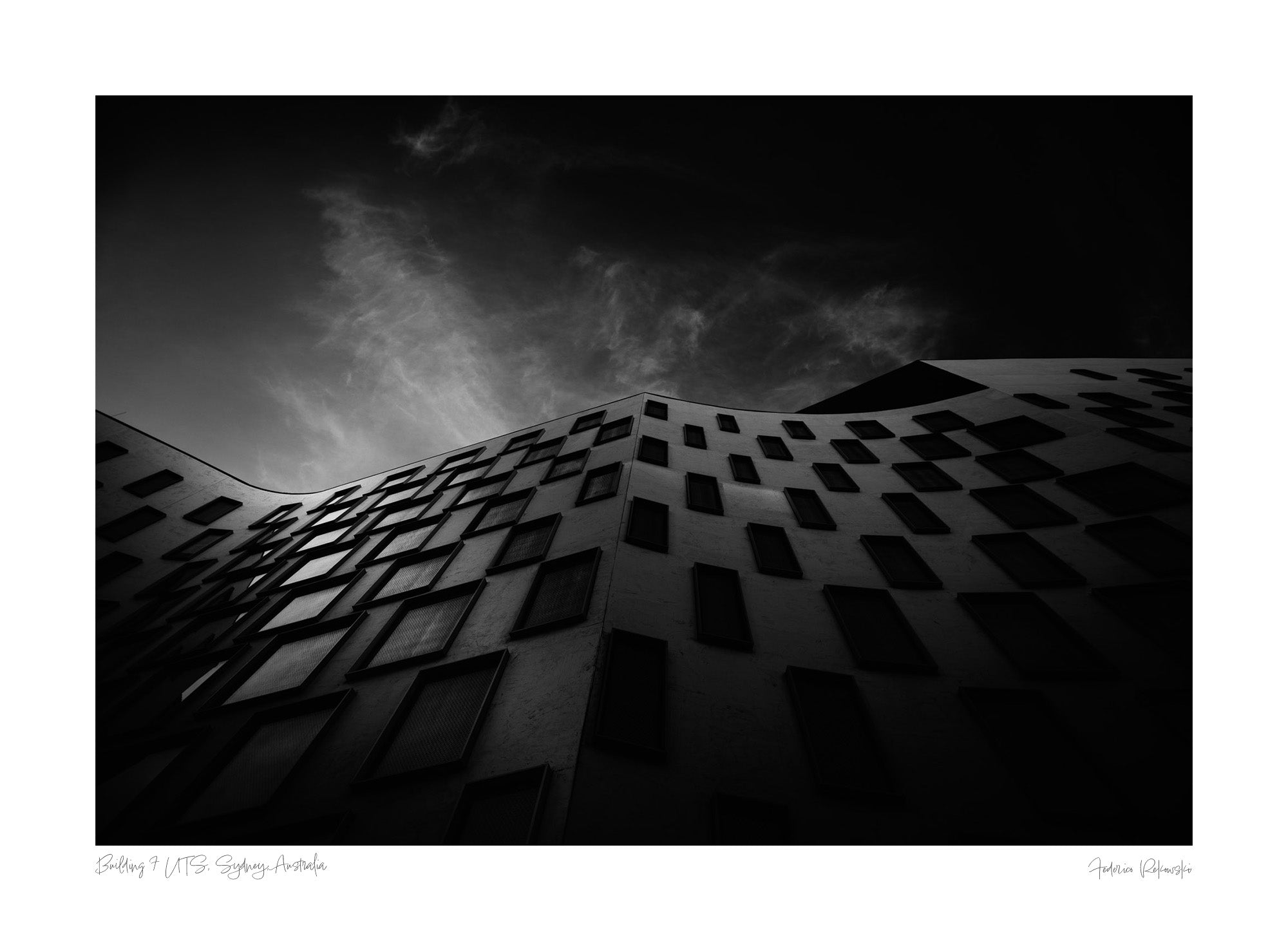 Silhouetted against the sky, the curved facade of the Vicki Sara Building at UTS, adorned with a pattern of dark windows.