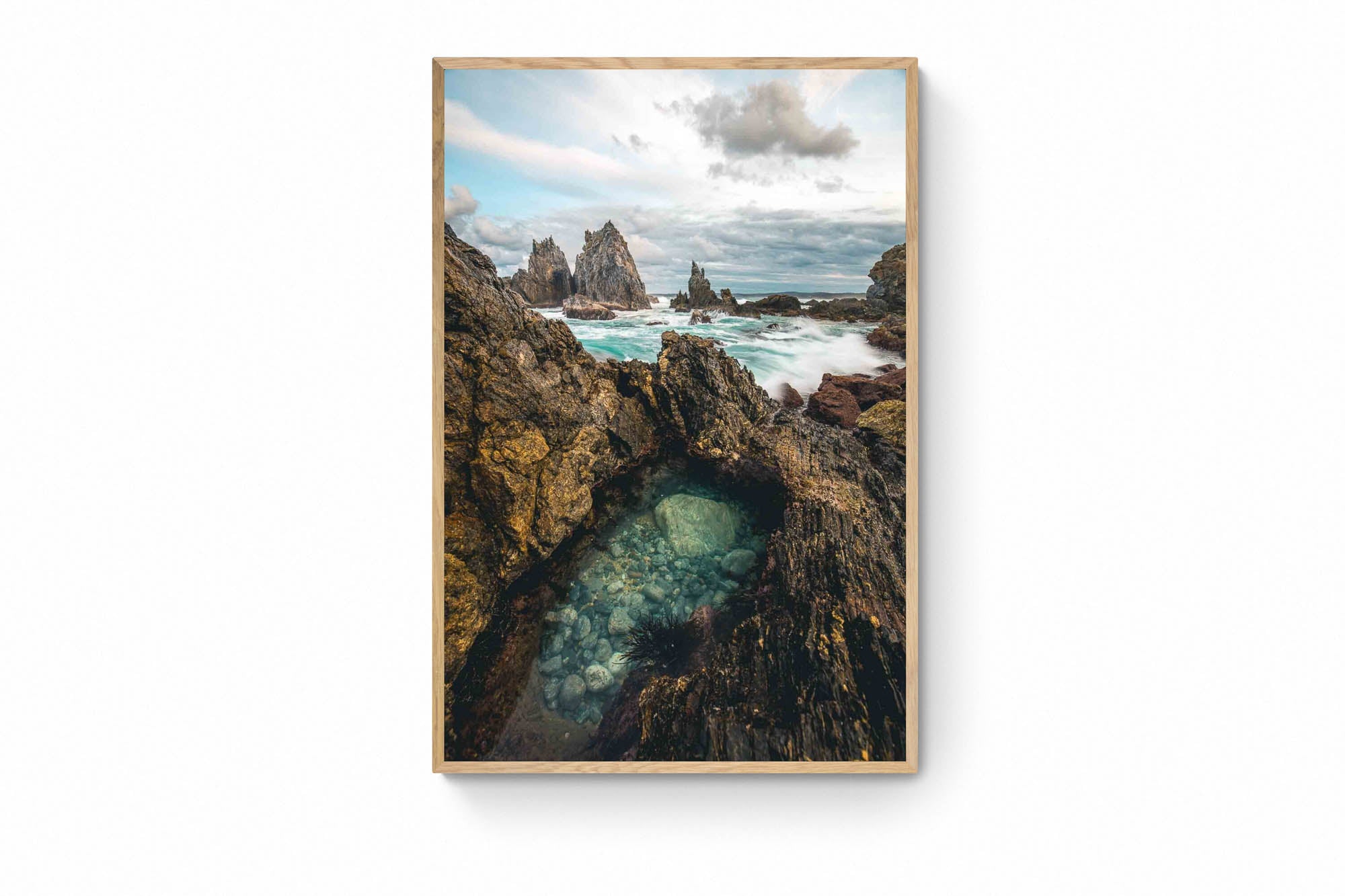 Rugged rock formations of Camel Rock in Bermagui with a natural tide pool in the foreground and turbulent sea in the background under a cloudy sky.