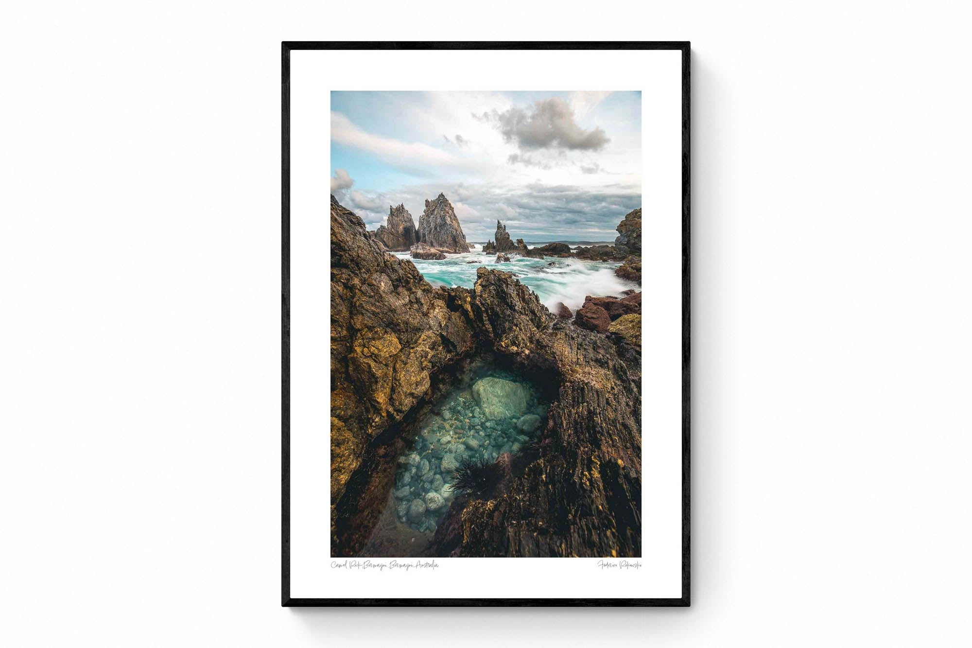 Rugged rock formations of Camel Rock in Bermagui with a natural tide pool in the foreground and turbulent sea in the background under a cloudy sky.