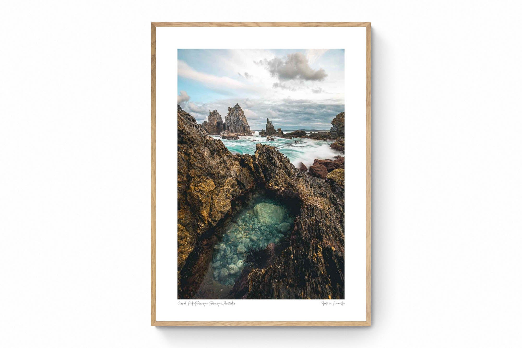 Rugged rock formations of Camel Rock in Bermagui with a natural tide pool in the foreground and turbulent sea in the background under a cloudy sky.