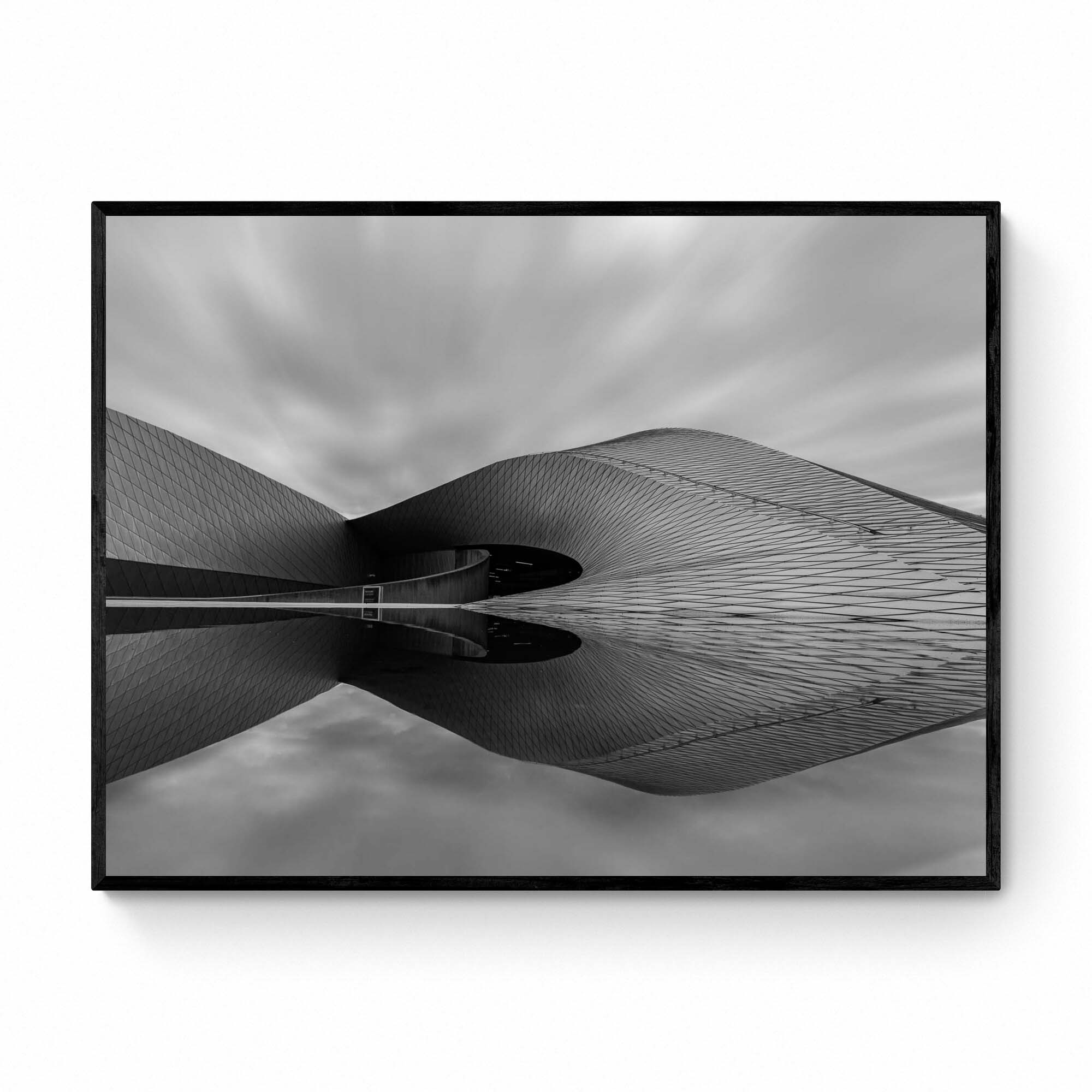 Black and white image of The Blue Planet Aquarium in Copenhagen with its reflective, wavy facade against a blurred sky.