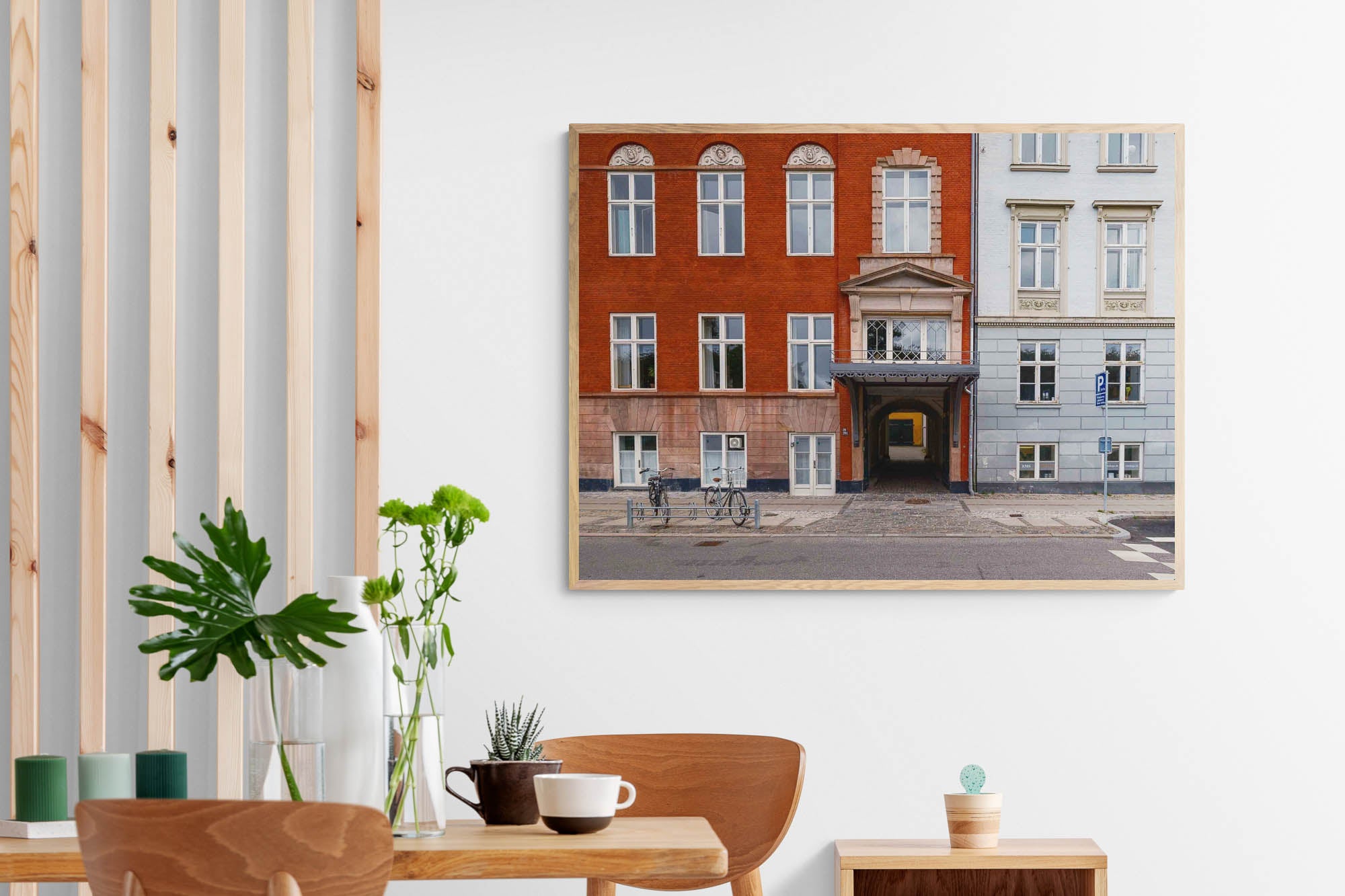 Colorful buildings in Copenhagen with a distinct red facade adjacent to a blue one, featuring a central archway leading to a hidden courtyard.