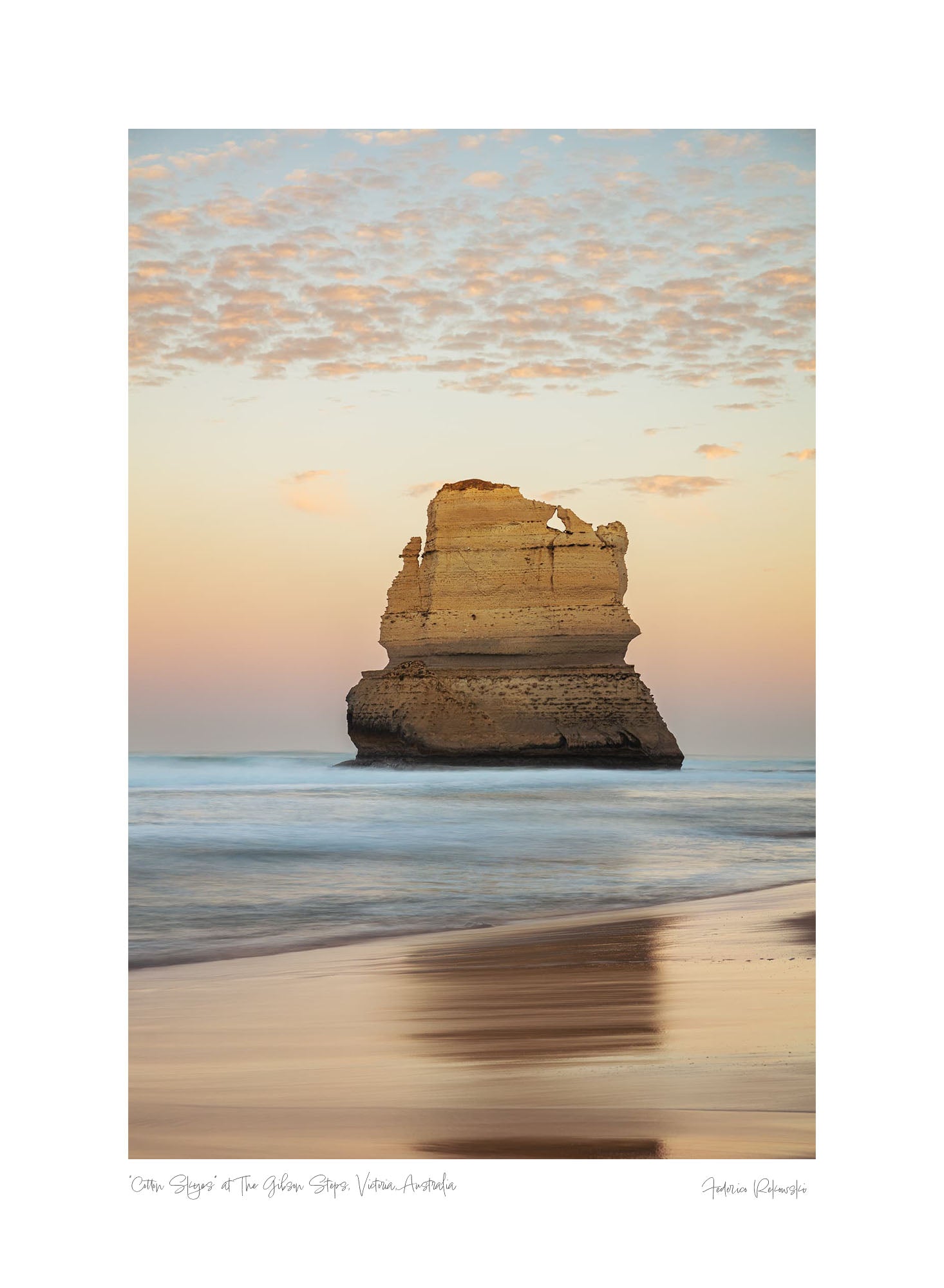 Early morning light casts a warm glow on a solitary limestone stack at Gibson Steps on Australia’s Great Ocean Road, with a soft sky and smooth waves.