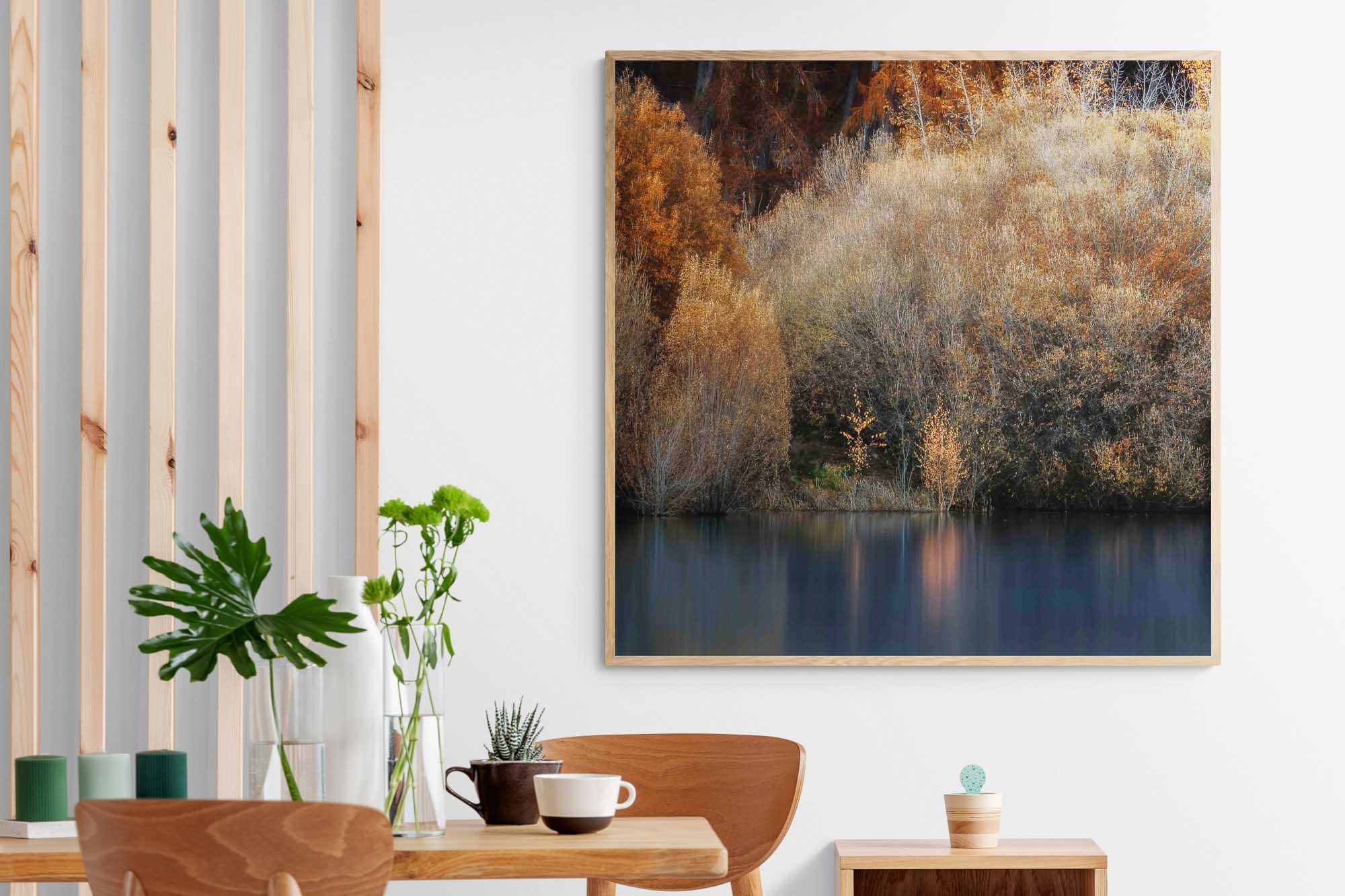 Golden autumn foliage by the peaceful shores of Lake Tekapo, New Zealand, with reflections in the calm water.