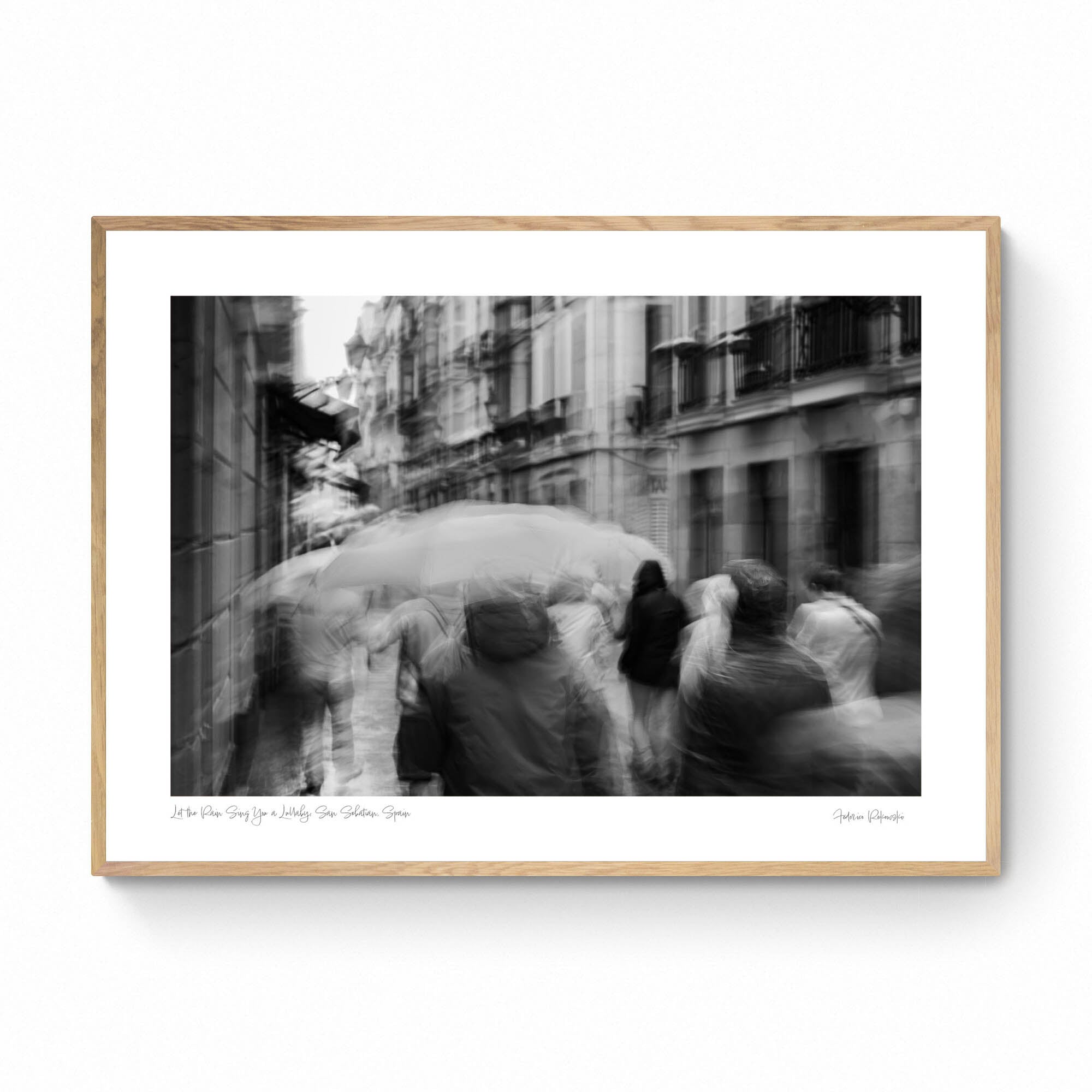 A monochrome image of pedestrians with umbrellas blurred by motion, embodying rain's lullaby in San Sebastian, inspired by Langston Hughes’ poetry.