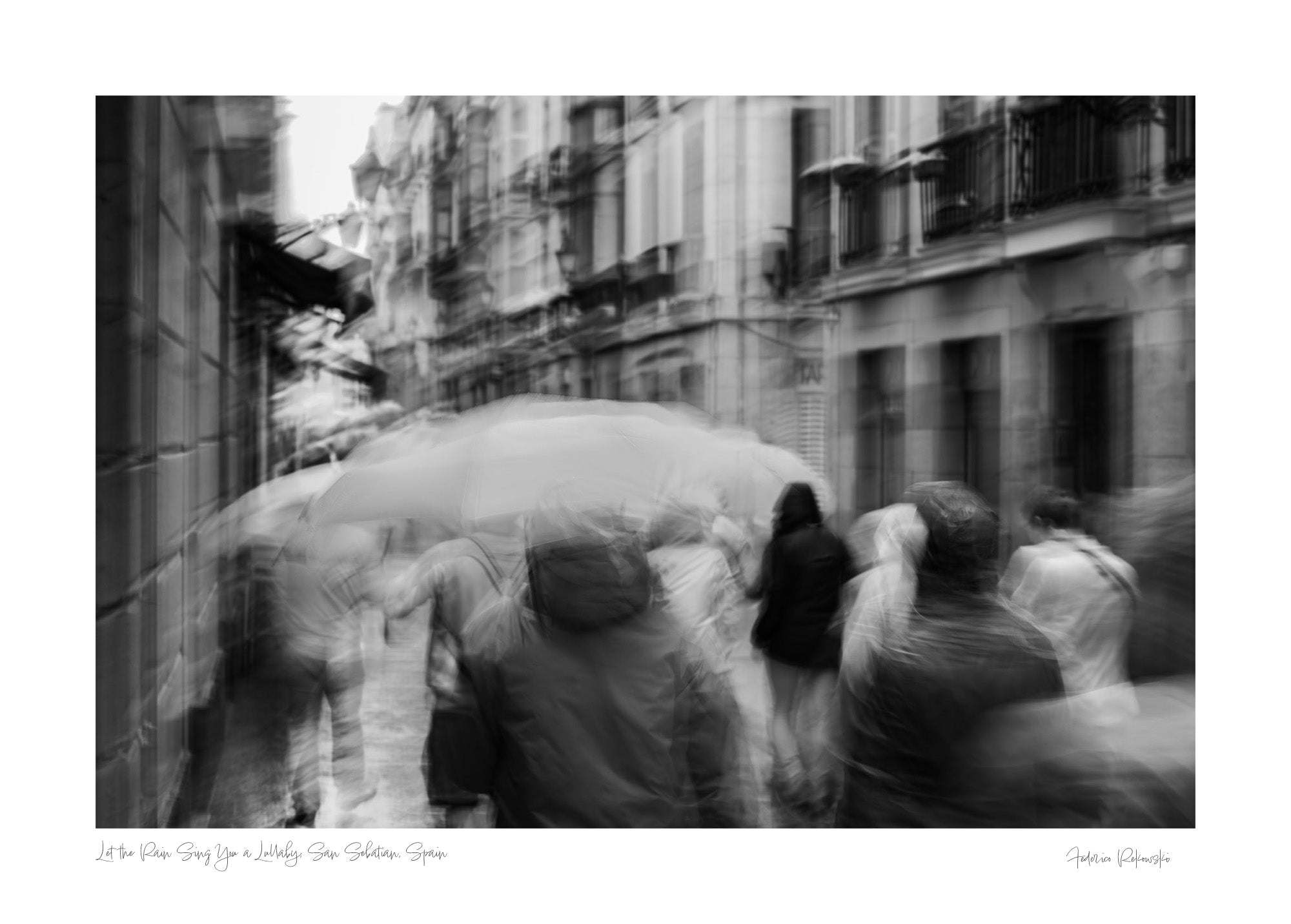 A monochrome image of pedestrians with umbrellas blurred by motion, embodying rain's lullaby in San Sebastian, inspired by Langston Hughes’ poetry.