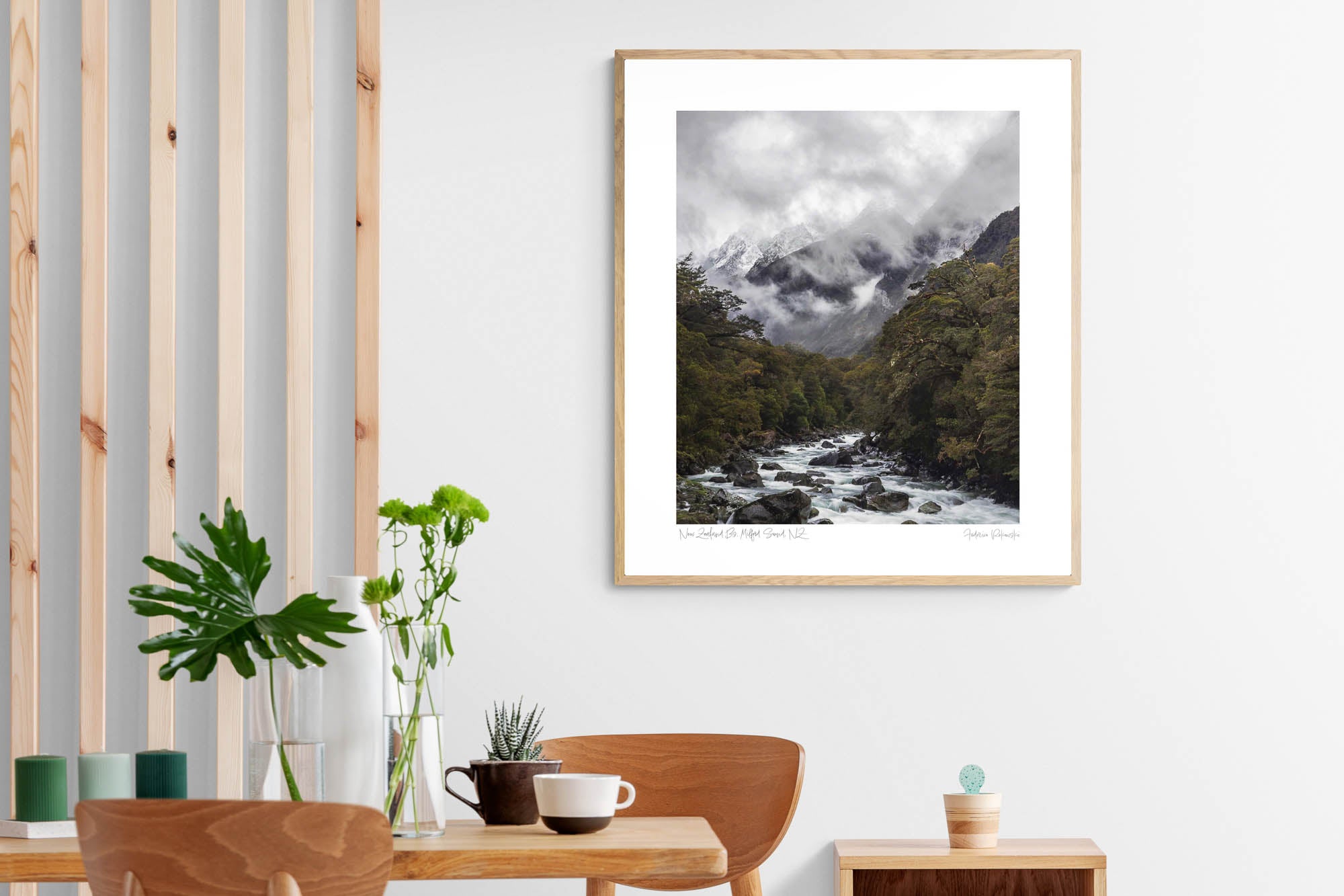 A powerful river cuts through a verdant forest with snow-covered mountains enshrouded in mist in the background at Milford Sound, New Zealand. Frame on a living Room