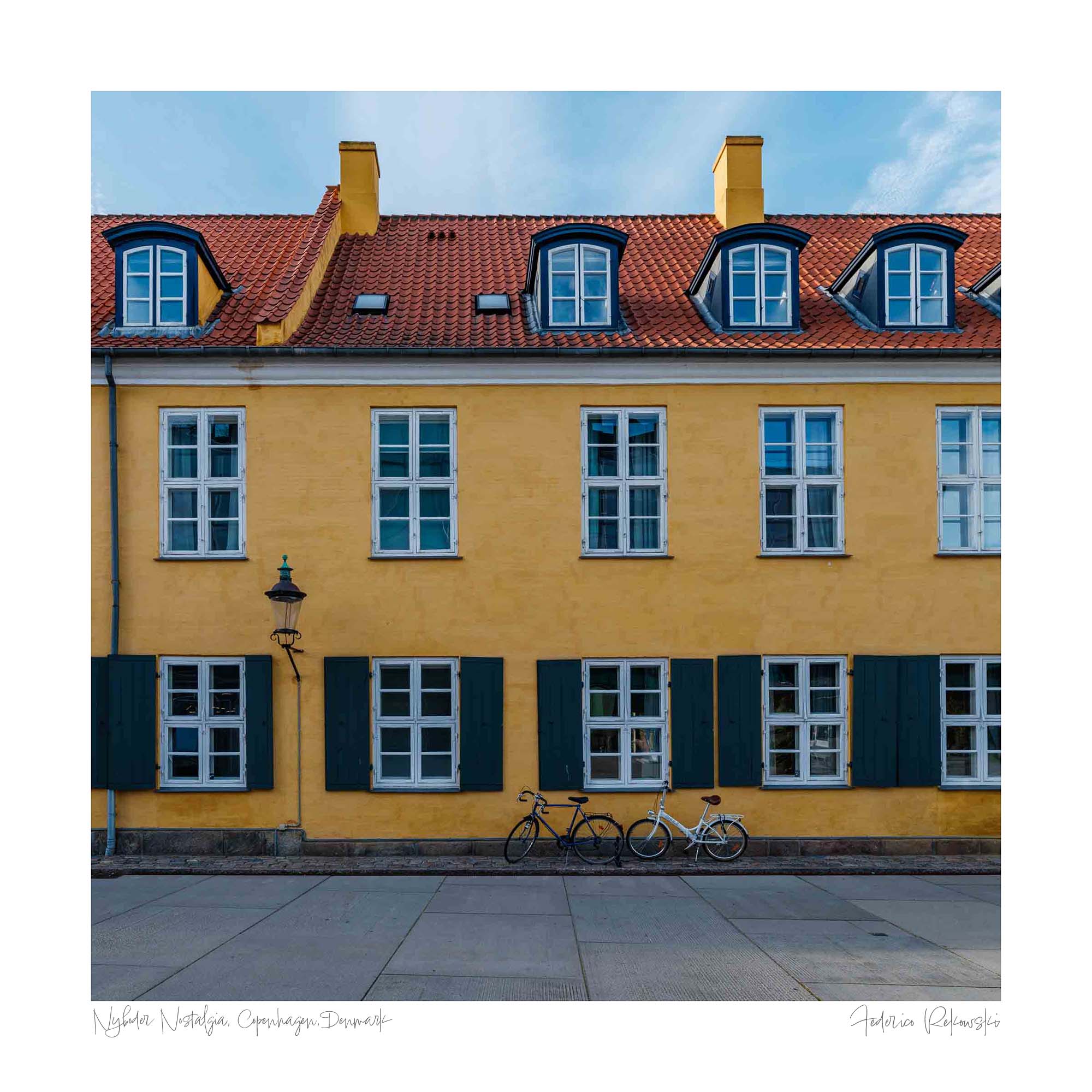 "Colorful image of a yellow building with green shutters and a bicycle in front on a street in Copenhagen, Denmark."