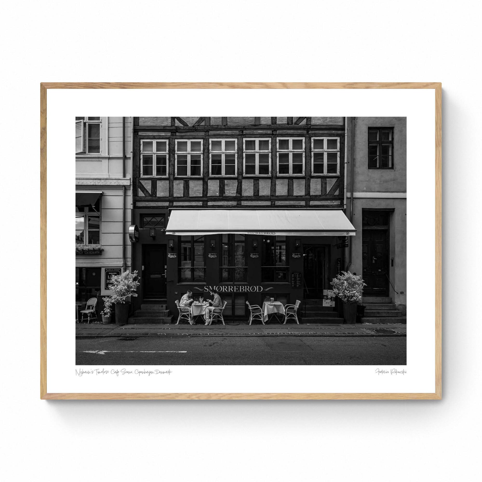 Black and white photo of a traditional Danish Smørrebrød café in Nyhavn, Copenhagen, with outdoor seating and historical buildings.