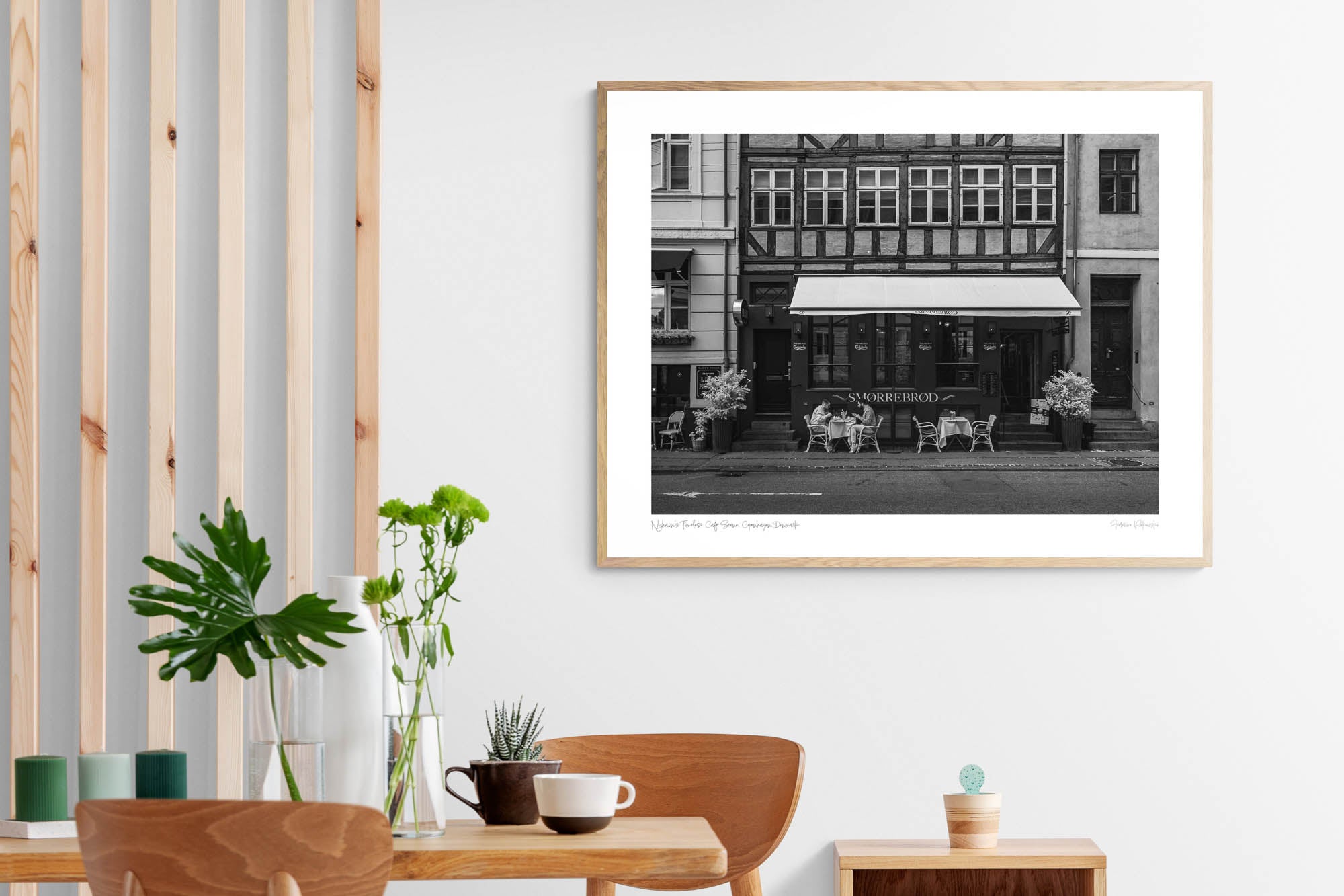 Black and white photo of a traditional Danish Smørrebrød café in Nyhavn, Copenhagen, with outdoor seating and historical buildings.