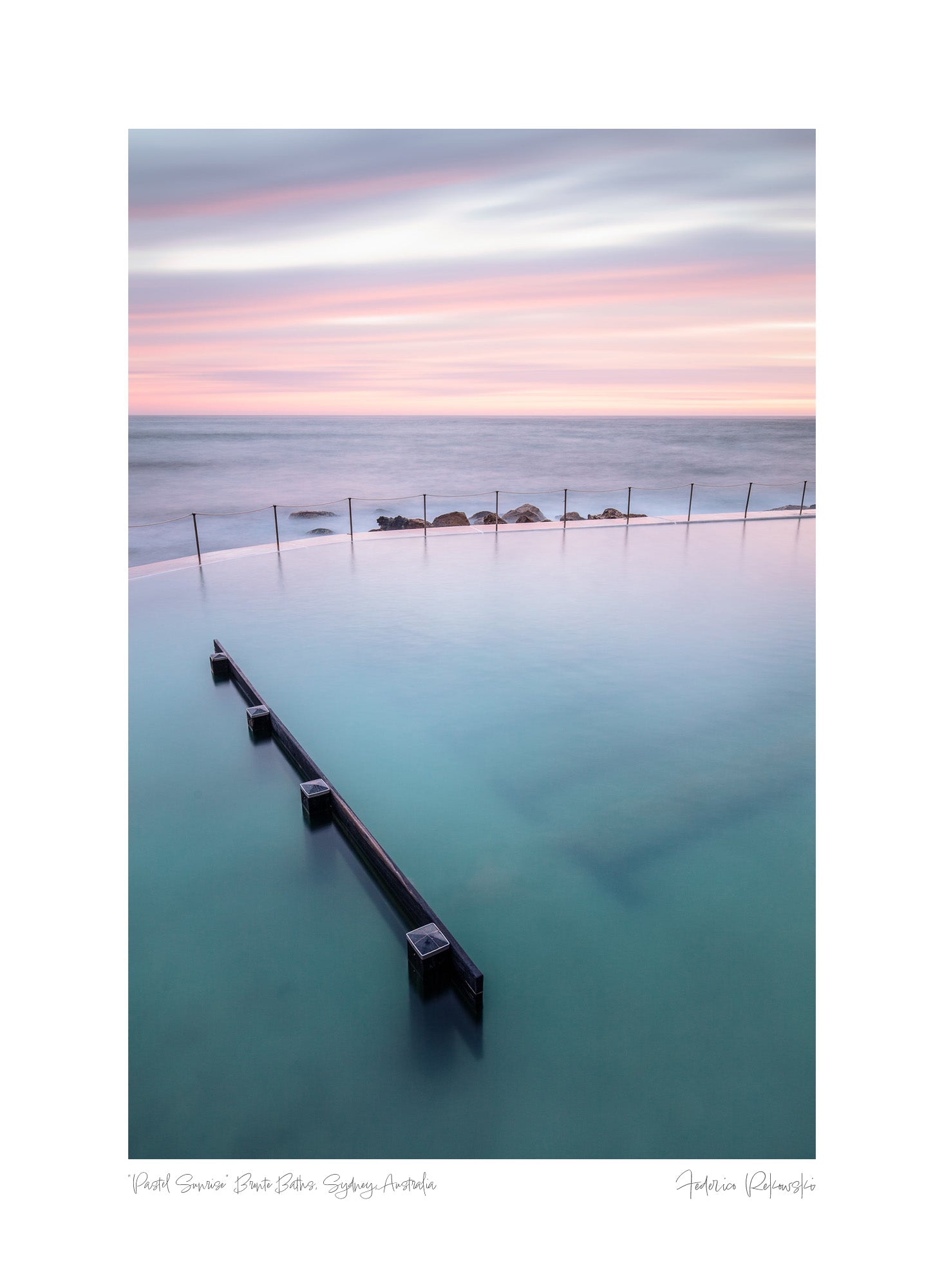 Long exposure of Bronte Baths in Sydney, with smooth waters under a pink and blue striped sky at twilight.