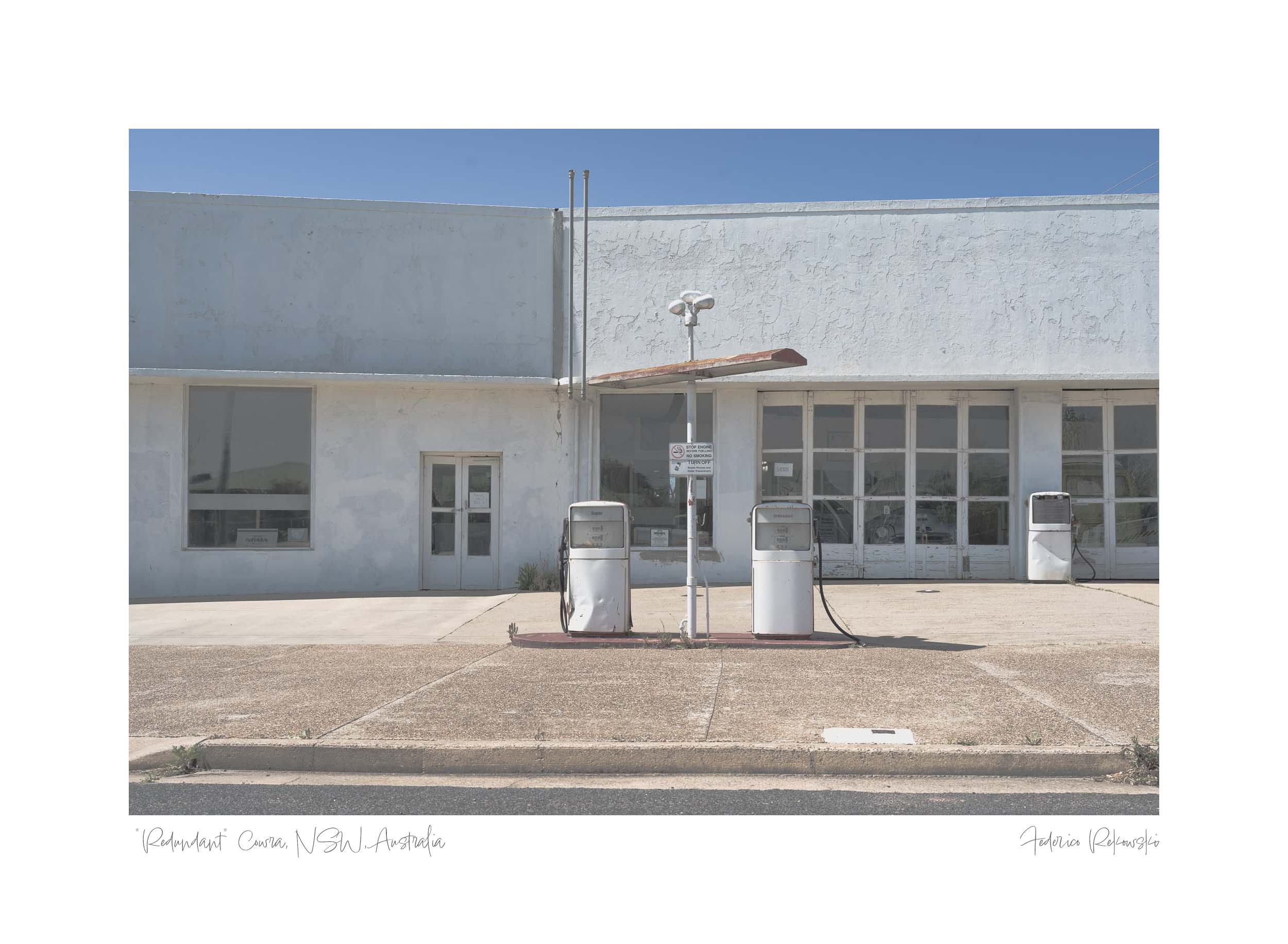 A desolate scene of an abandoned fuel station with obsolete pumps in Cowra, NSW, under a broad daylight sky.