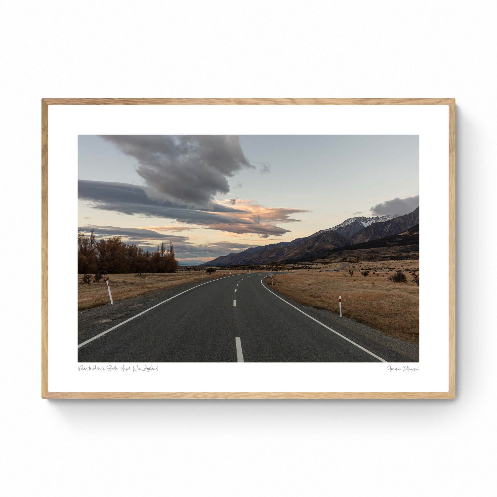 A serene landscape photograph of a road in New Zealand with Aoraki/Mt Cook in the background under a twilight sky with dynamic cloud formations.