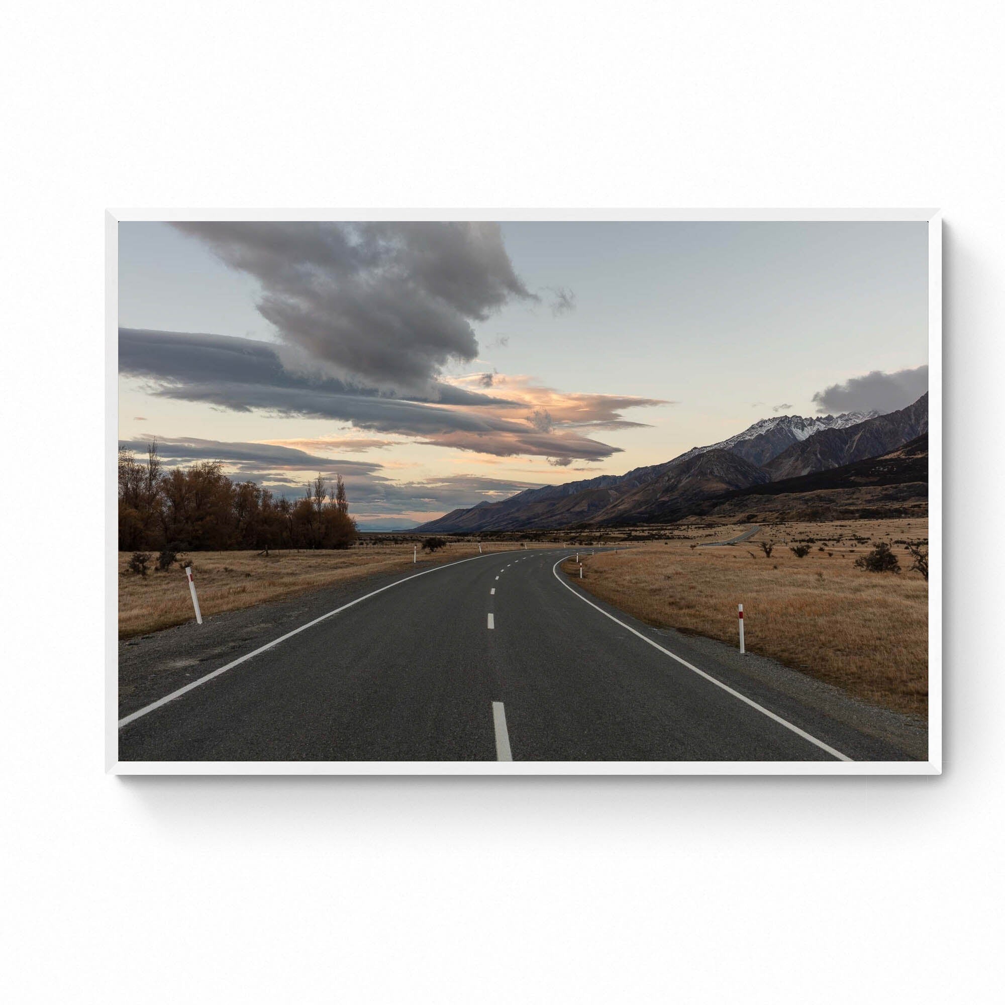 A serene landscape photograph of a road in New Zealand with Aoraki/Mt Cook in the background under a twilight sky with dynamic cloud formations.