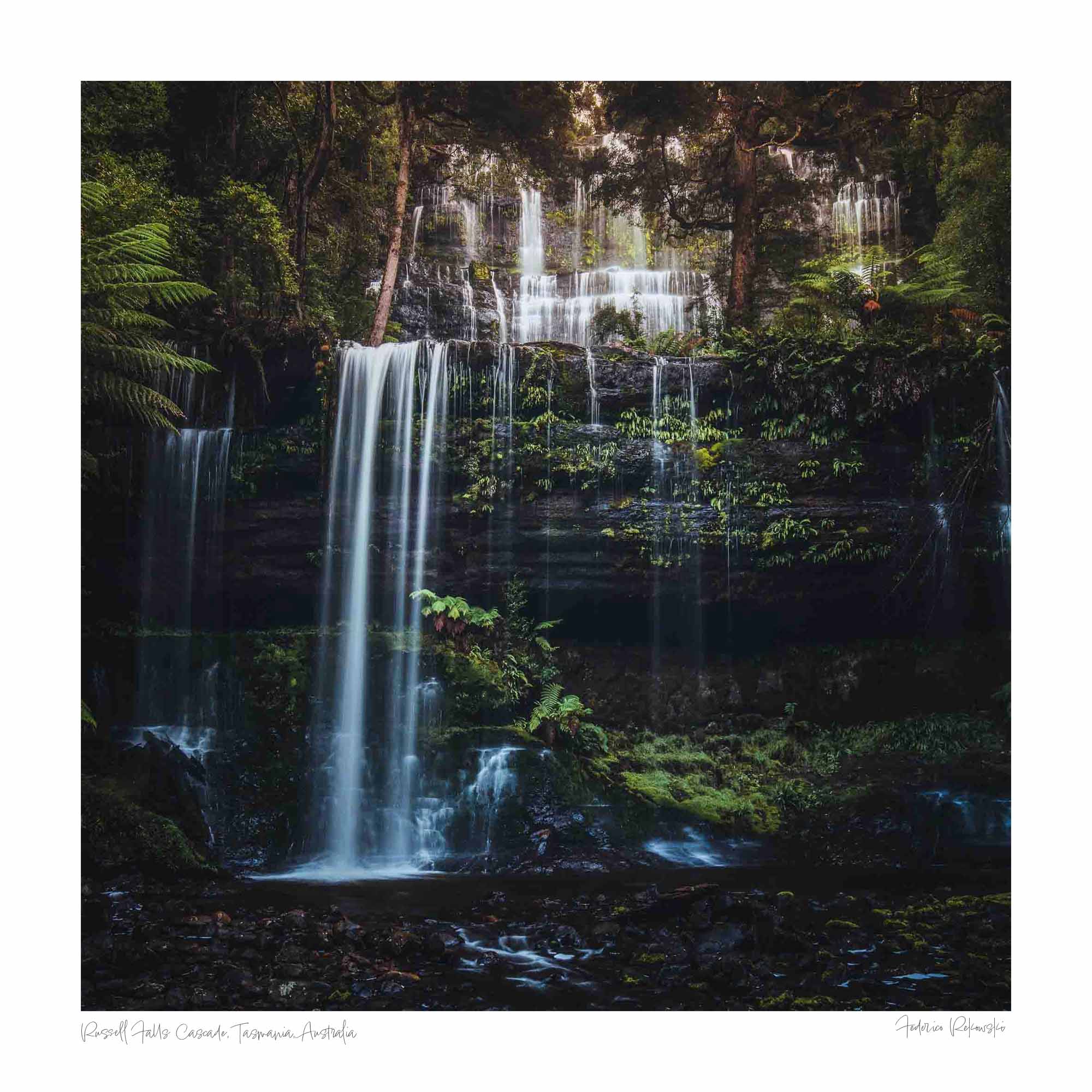 Long exposure photo of the multi-tiered Russell Falls in Tasmania, surrounded by a lush, fern-draped forest.