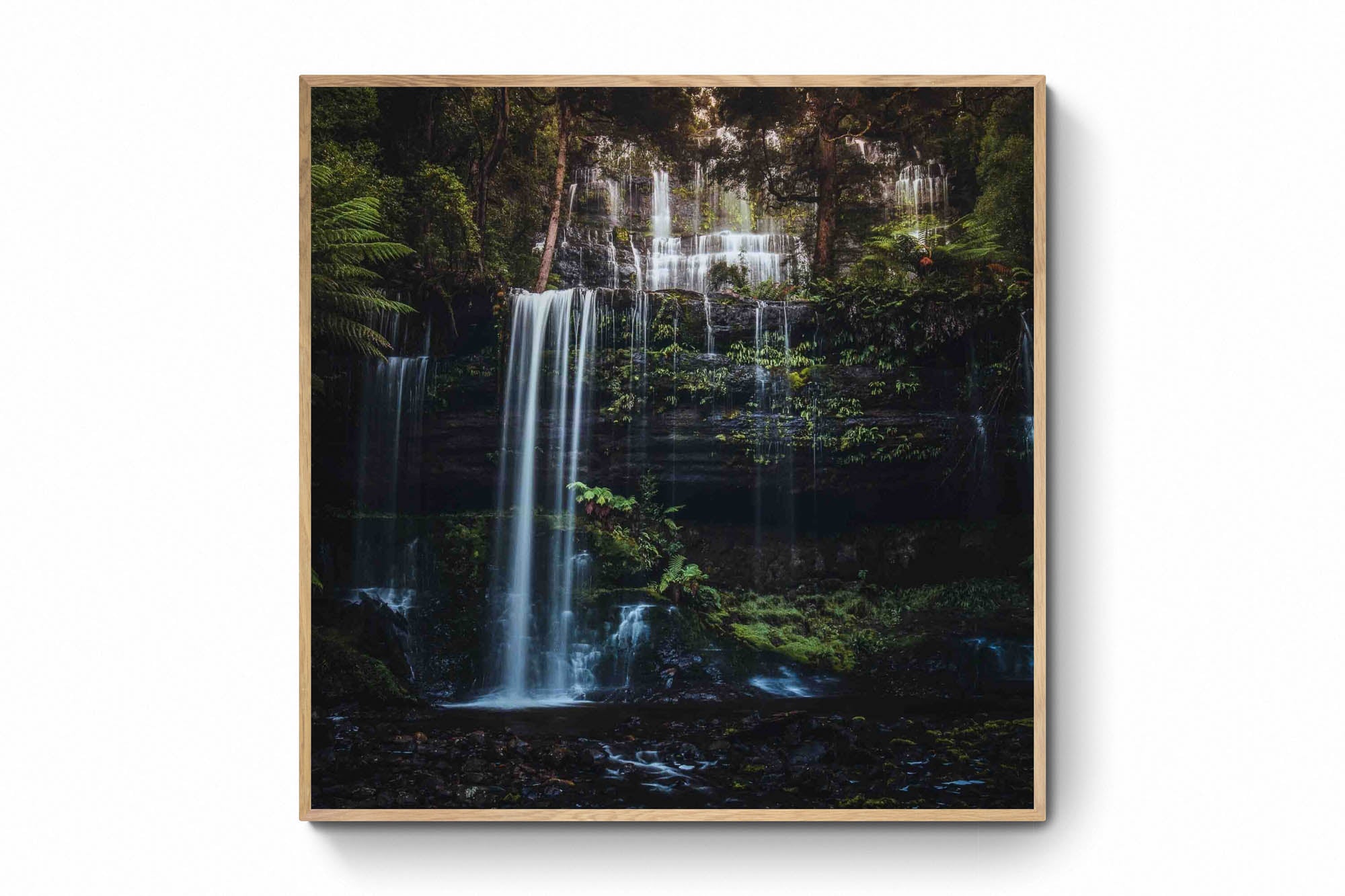 Long exposure photo of the multi-tiered Russell Falls in Tasmania, surrounded by a lush, fern-draped forest.