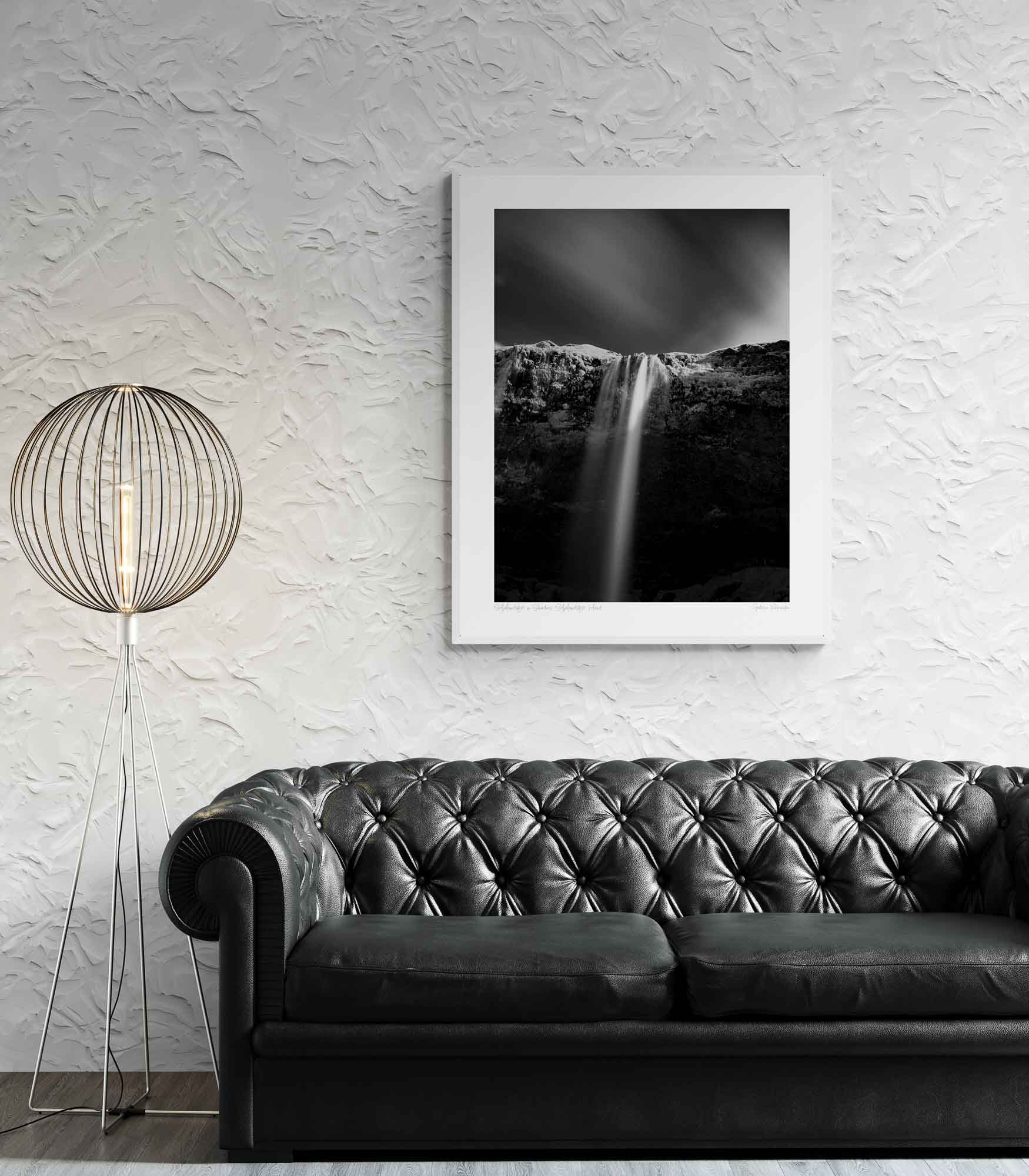 A black and white long-exposure photograph of Seljalandsfoss waterfall in Iceland, showing smooth water streams against a dark, textured cliff.