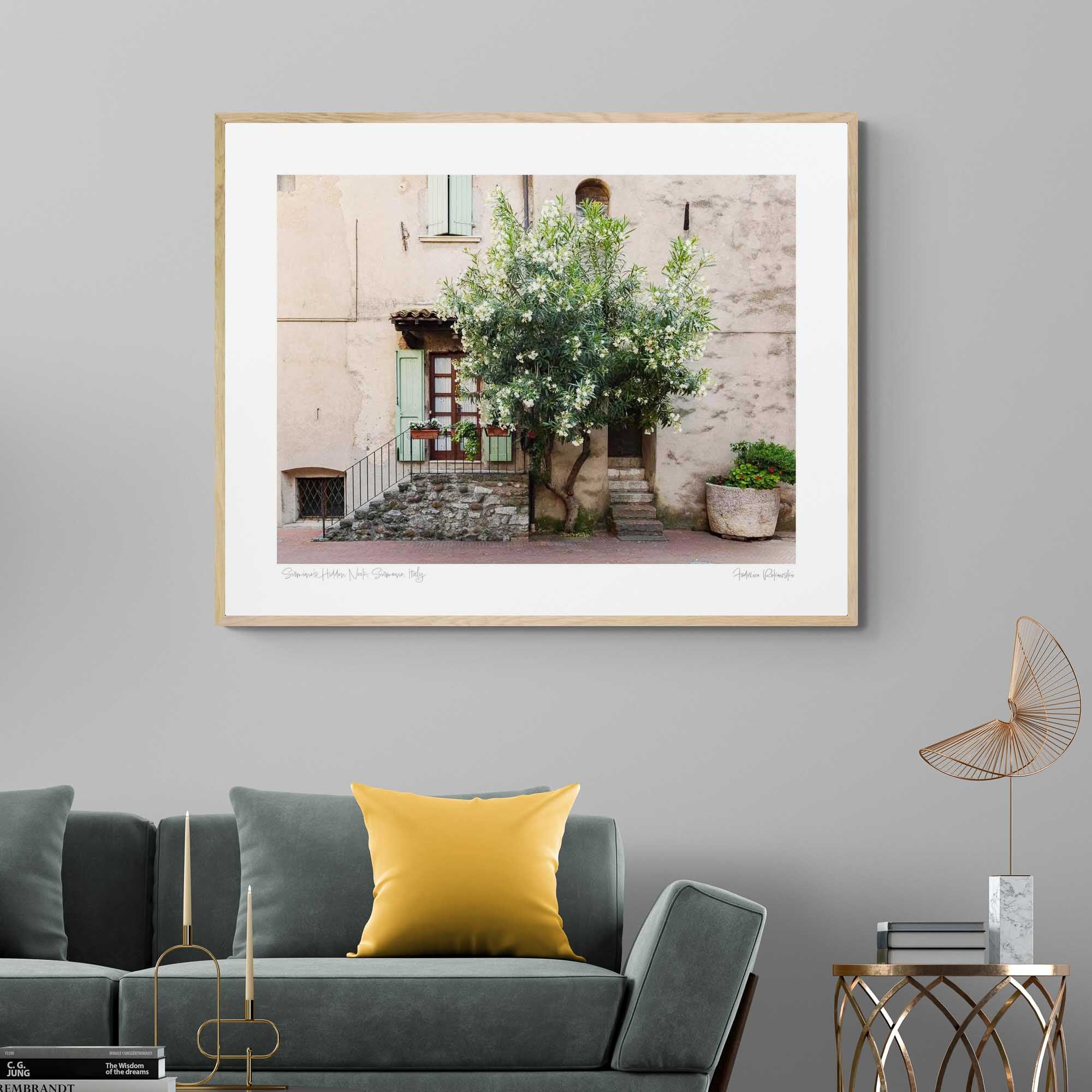 Quaint Italian house with a flowering oleander tree, stone steps, green shutters, and a large potted plant in Sirmione, Italy.