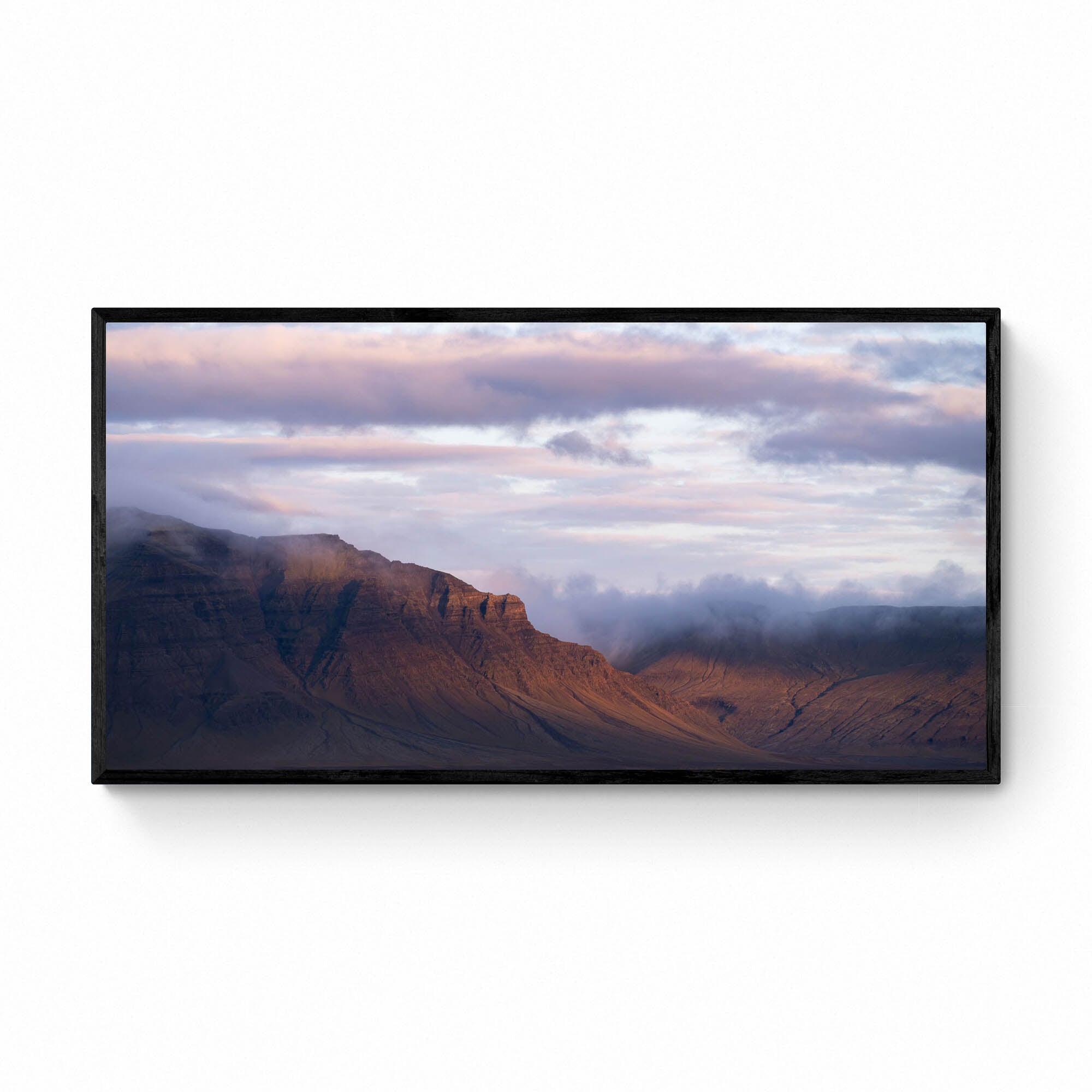 Late evening light bathes the Snæfellsnes Peninsula mountains in a warm glow with pink-tinged clouds above in Iceland.