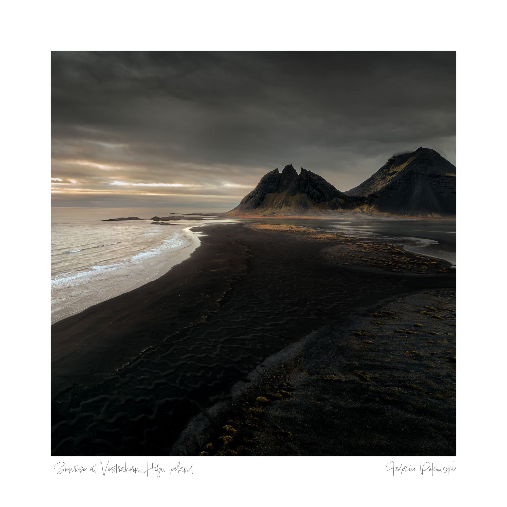 Sunset at Vestrahorn, Iceland, with the mountain's silhouette against a dramatic sky and patterns in the dark sand leading to the sea.