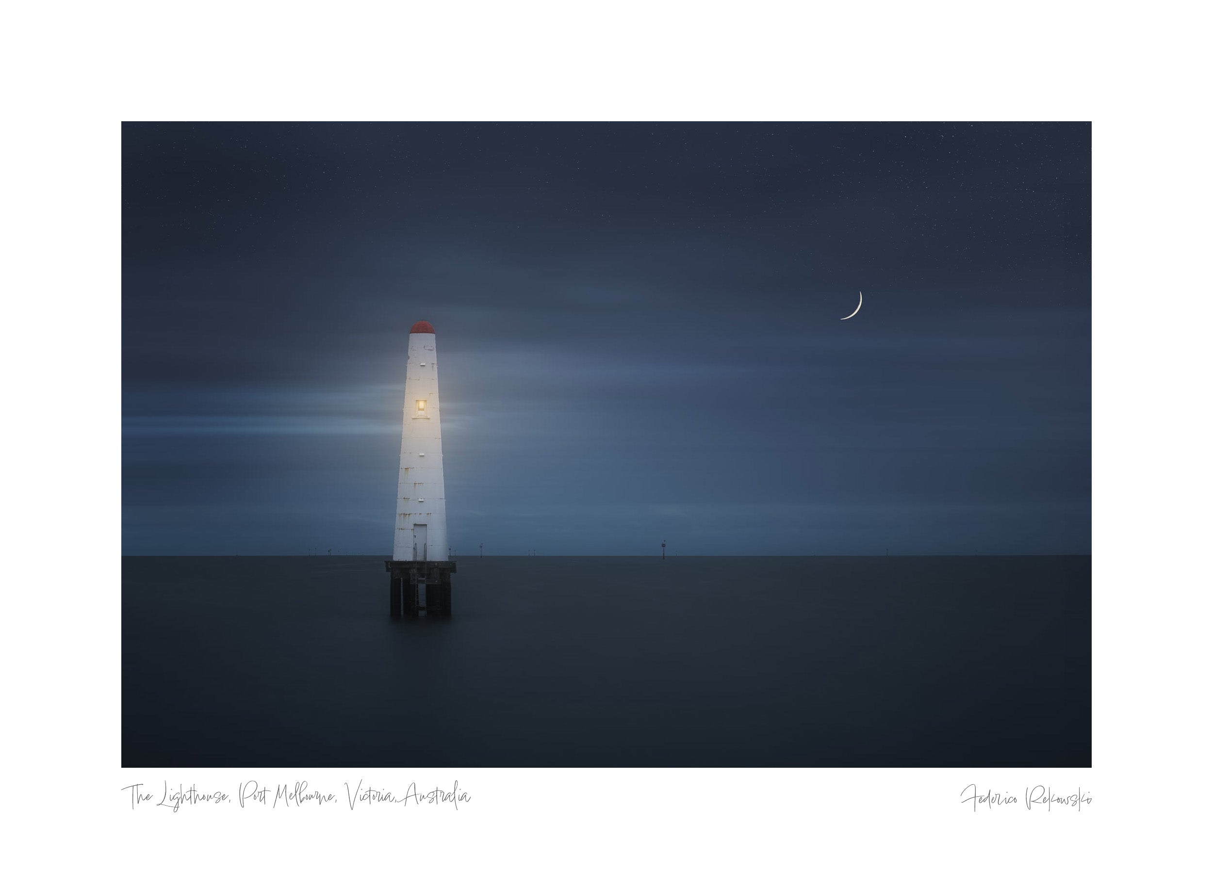 A lone lighthouse illuminated on Princess Pier in Melbourne against a starry night sky with a crescent moon.