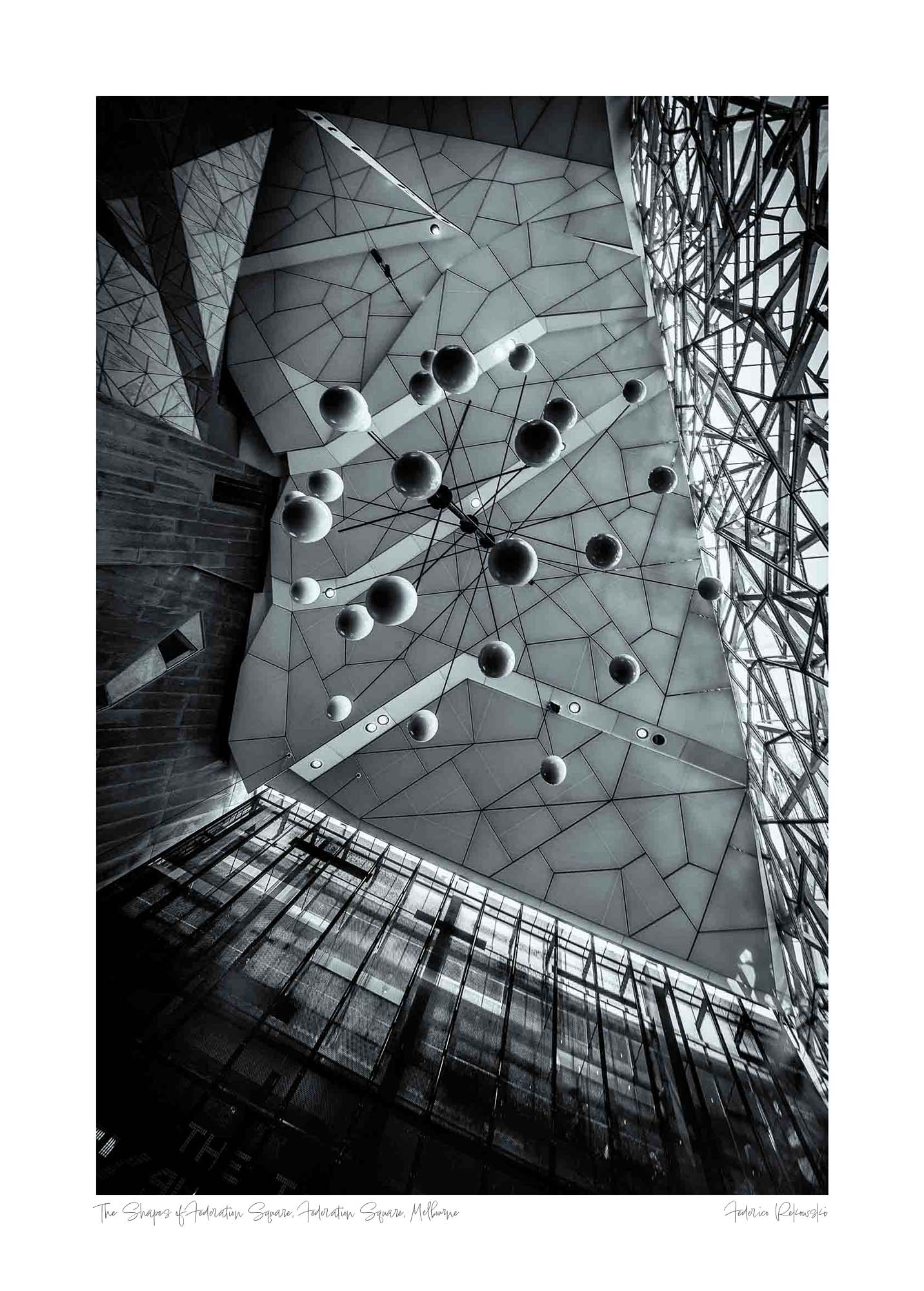 Black and white photo of the abstract geometric ceiling at Federation Square in Melbourne, with spherical elements hanging against the angular design.